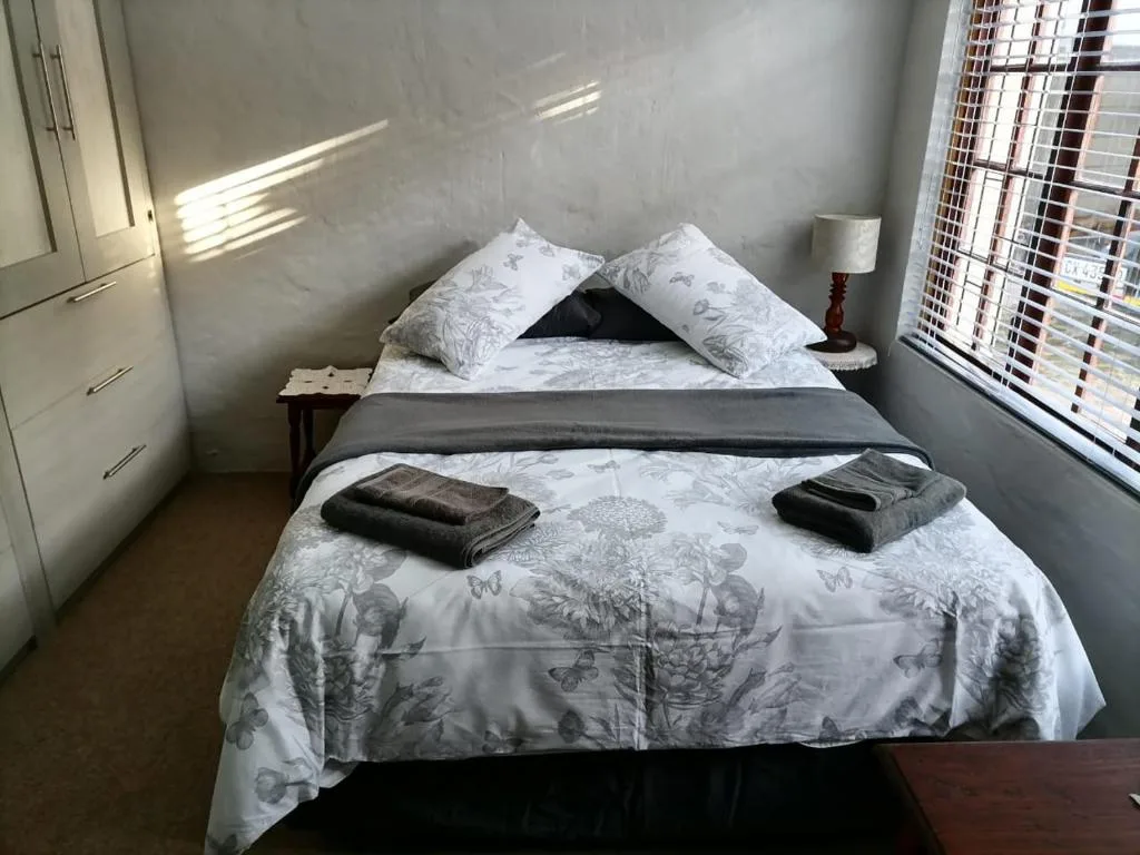 Bright bedroom with neatly made bed and patterned bedding, soft natural light