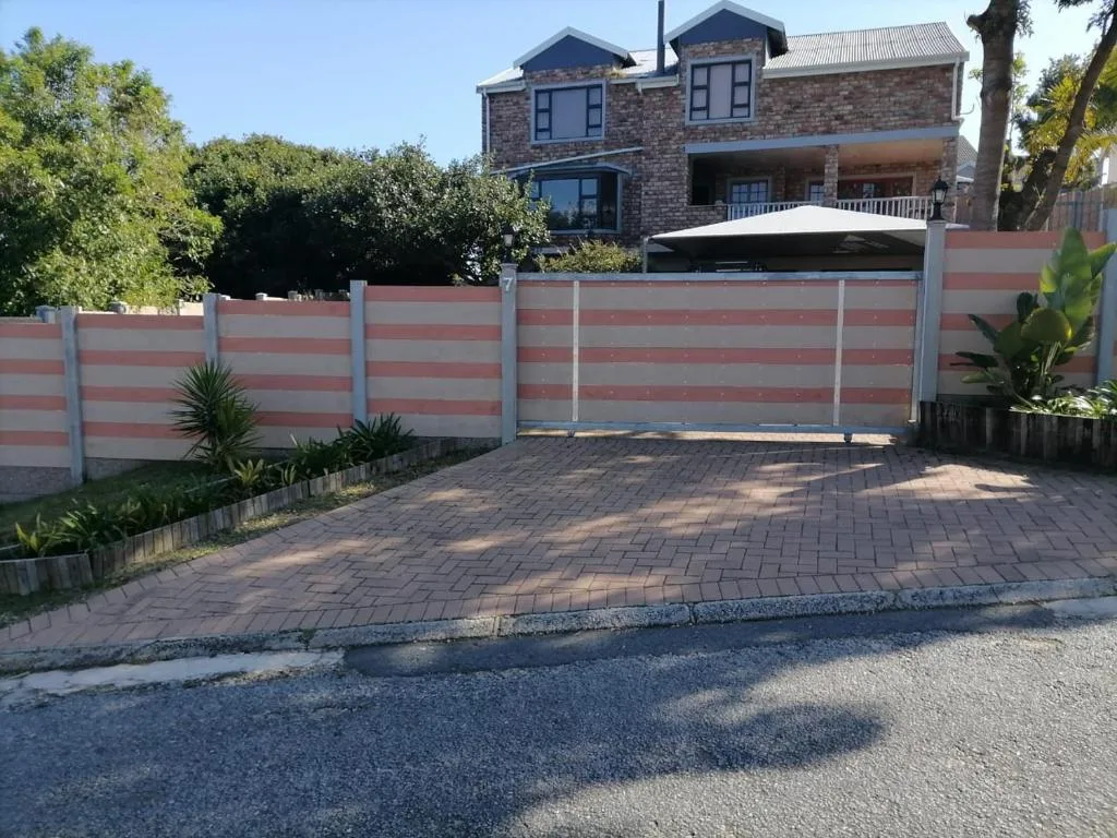 Two-story brick house with striped fence and paved driveway entrance