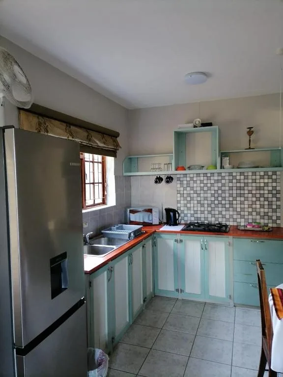 Bright kitchen with turquoise cabinetry, orange countertops, and tiled backsplash