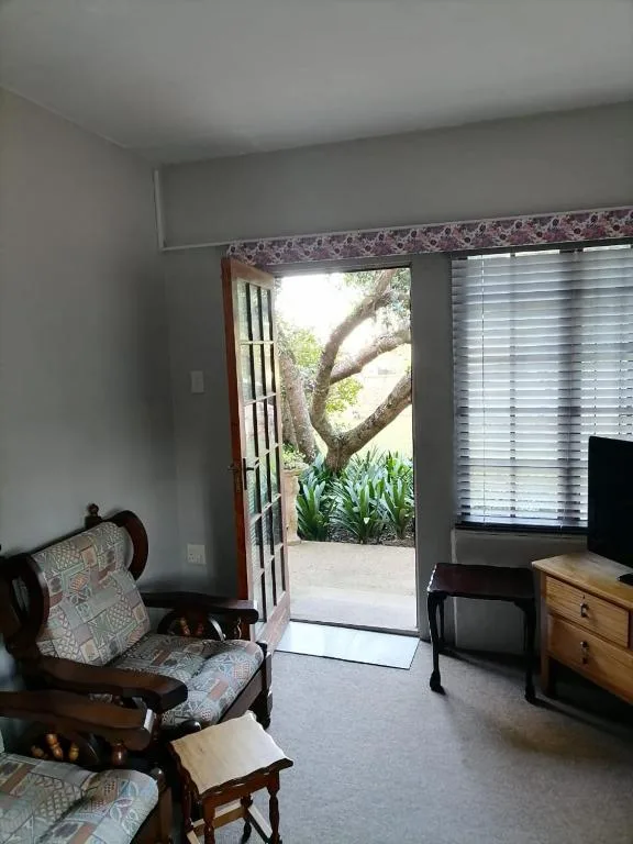 Spacious lounge with wooden furniture and outdoor garden view access