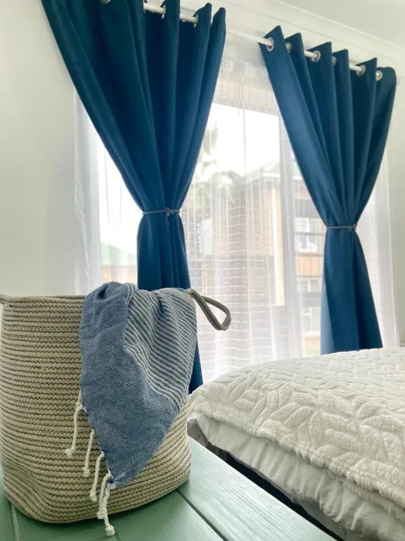 Bedroom with blue curtains, woven basket, and quilted bedding visible