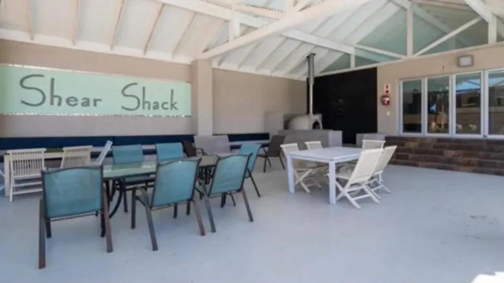 Covered outdoor deck with dining tables and seating area overlooking water