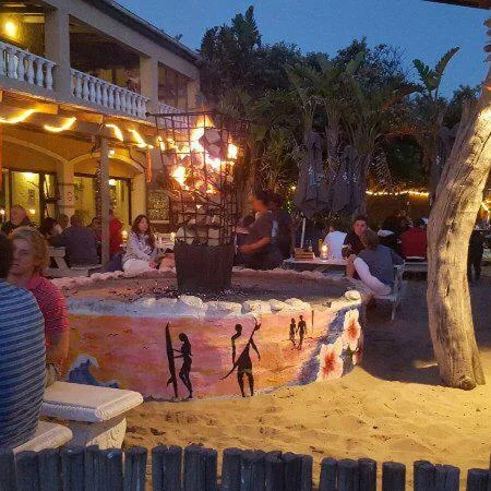 Beachfront entertainment area with sand, seating, and evening lighting