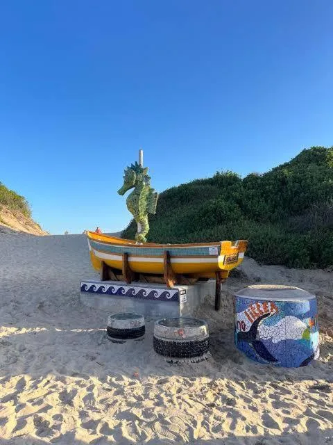 Colorful decorative boat sculpture on beach sand with artistic elements