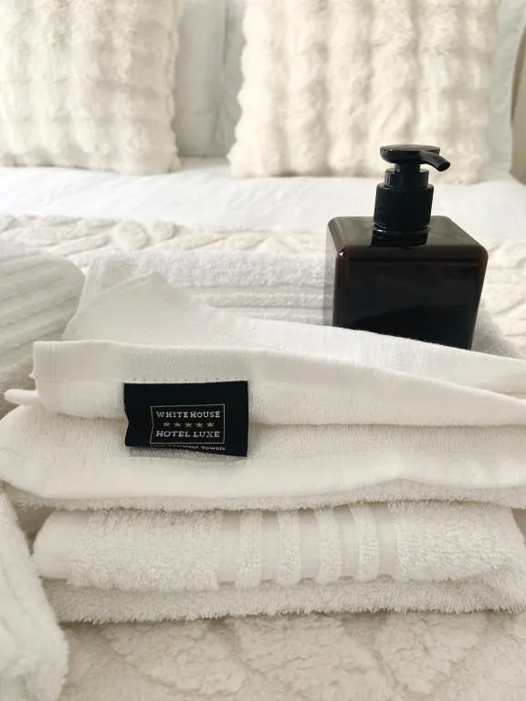 Luxury hotel toiletries and white fluffy towels artfully arranged on bed