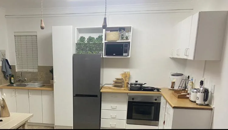 Modern kitchen with white cabinetry, black appliances, wooden counters, and pendant lighting