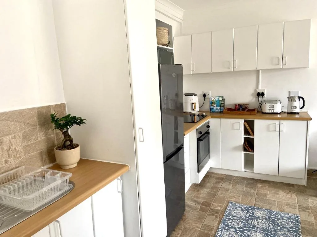 Modern white kitchen with wooden countertops, black appliances, and storage cabinets