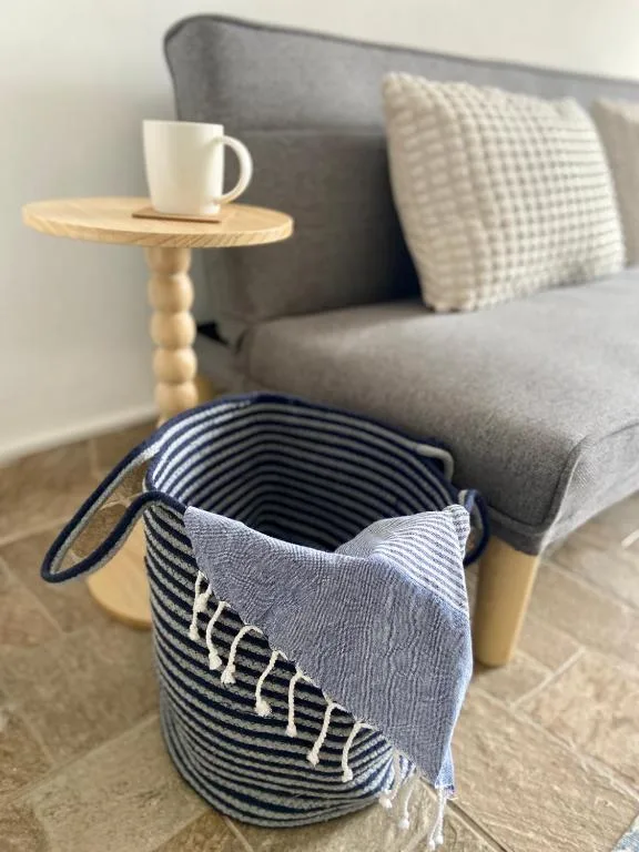 Gray upholstered sofa with textured pillows and wooden side table with mug