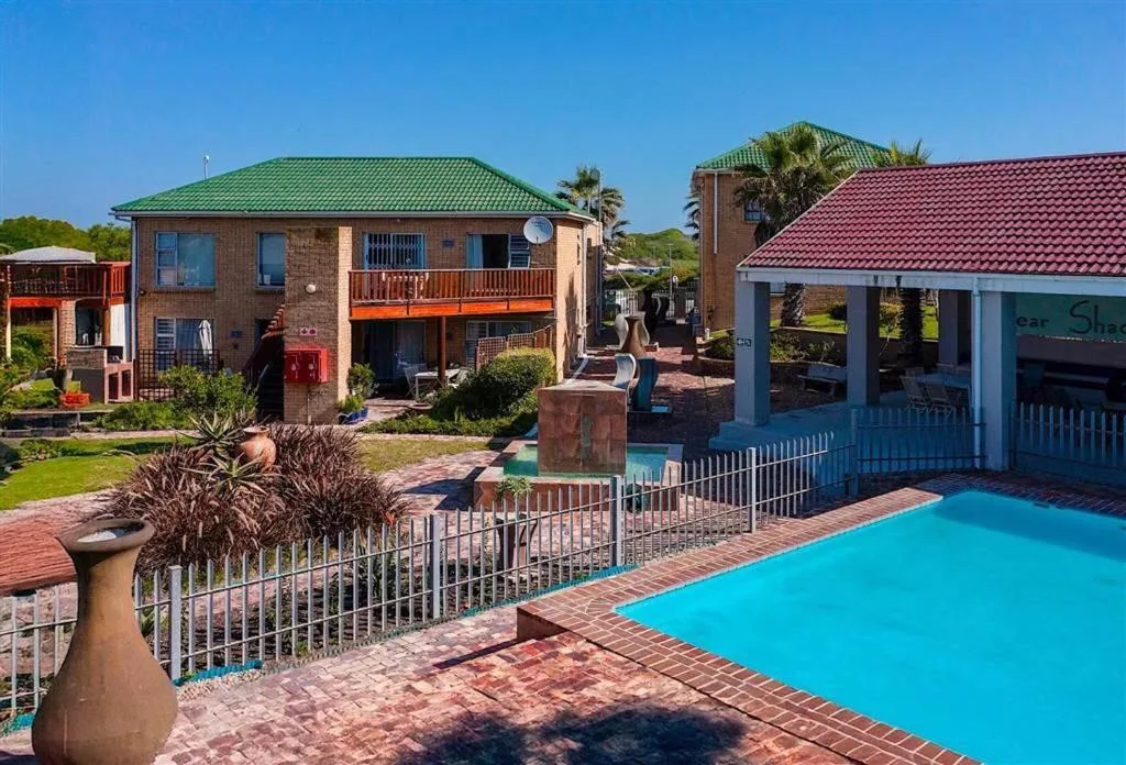 Bright turquoise swimming pool with brick surround and safety fencing