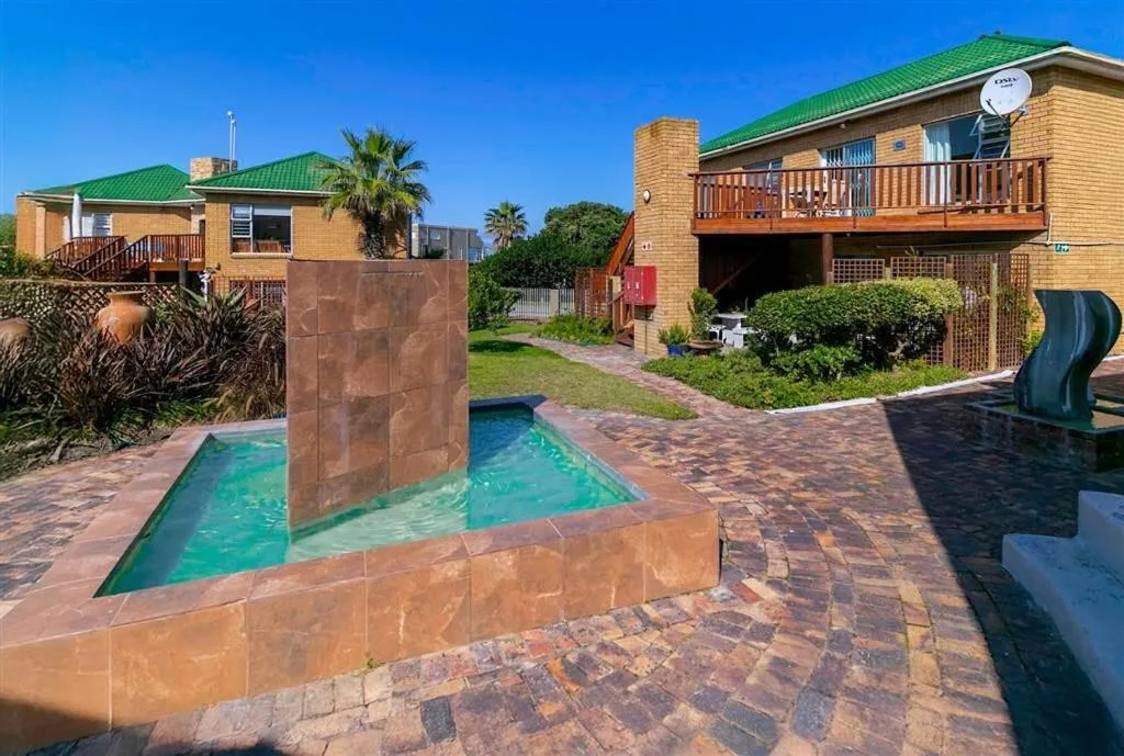 Small swimming pool with artistic stone feature in paved courtyard area