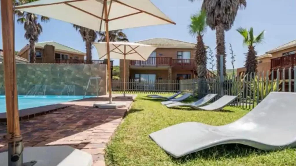 Swimming pool with loungers, umbrellas, and manicured lawn area