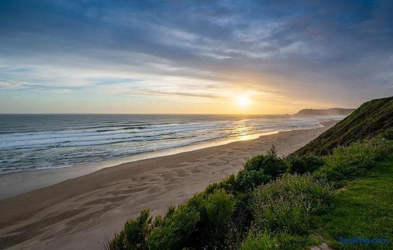 Sunset over golden beach and ocean with coastal cliffs visible