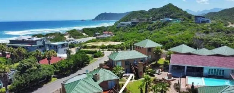 Aerial view of coastal property with ocean, beach, and lush green mountains