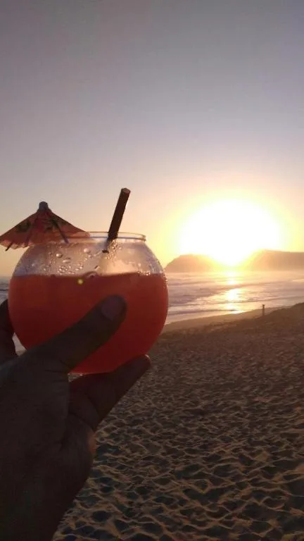 Sunset cocktail on beach with ocean and mountains beyond