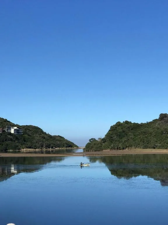 Calm lagoon waters with forested hills and clear blue sky