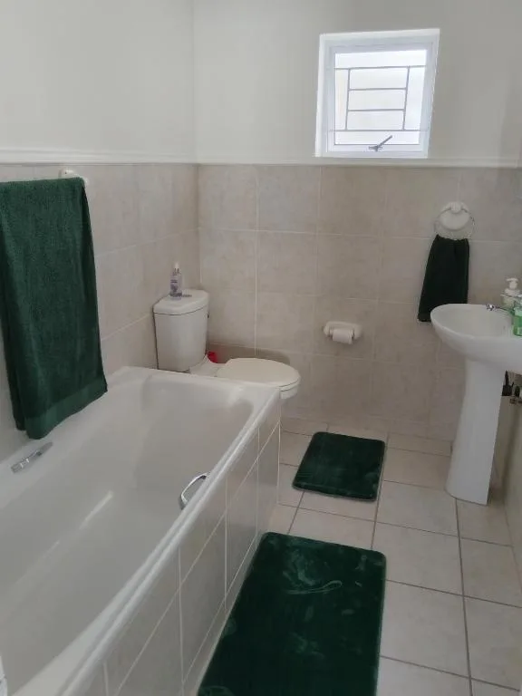 Clean bathroom with bathtub, pedestal sink, and small window