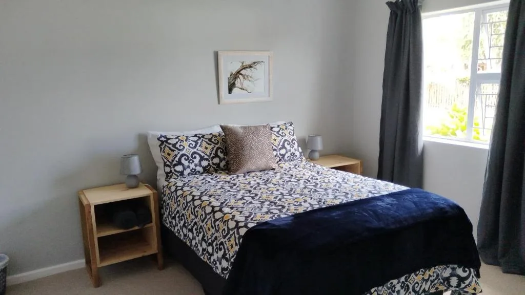 Bright bedroom with patterned bedding, wooden nightstands, and garden views