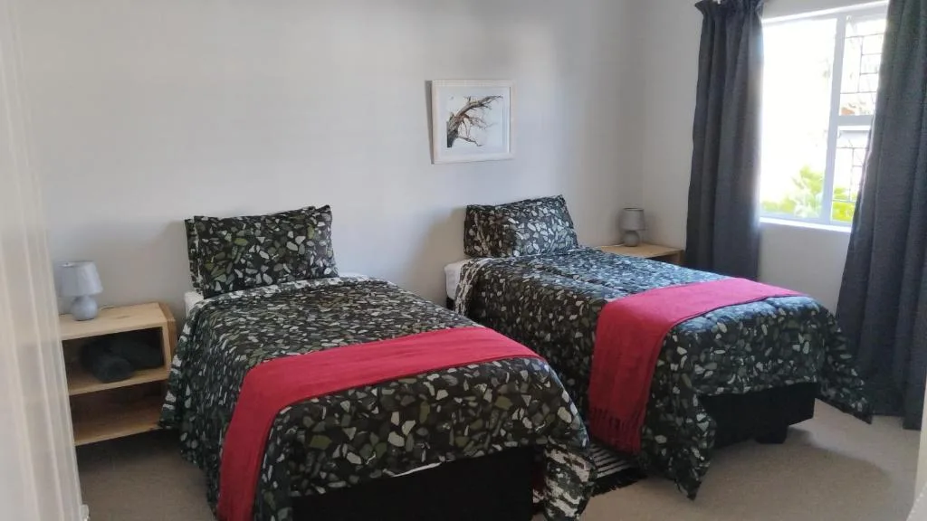 Bright bedroom with two single beds, patterned bedding, and natural light