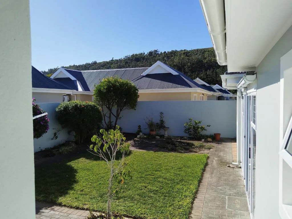 White cottage with navy roof and landscaped garden courtyard area