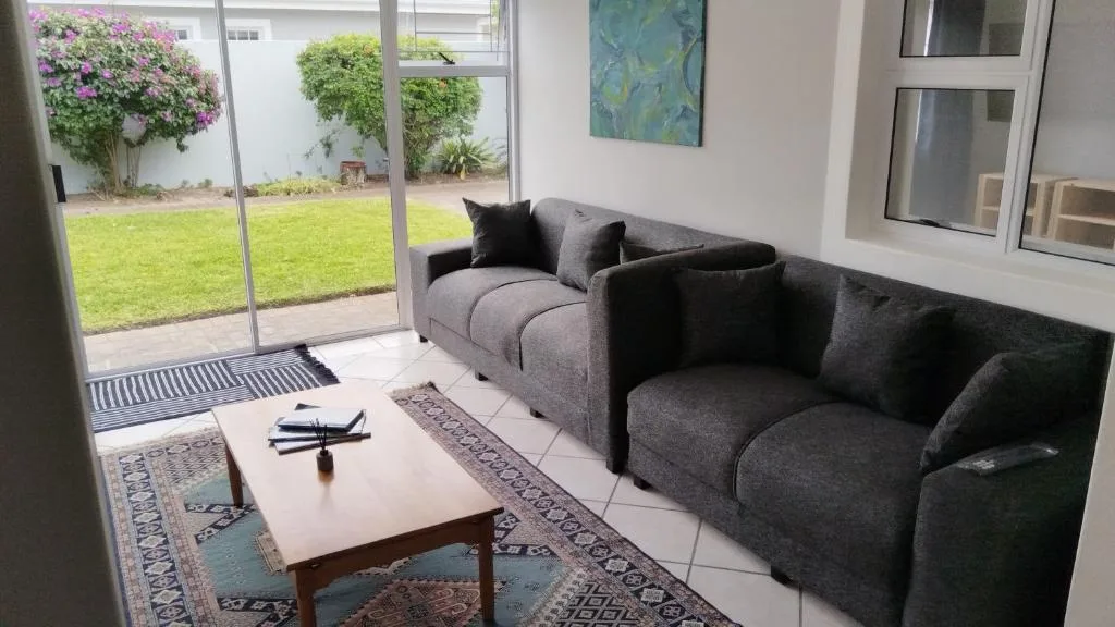 Modern lounge with grey sofas overlooking manicured garden through glass doors