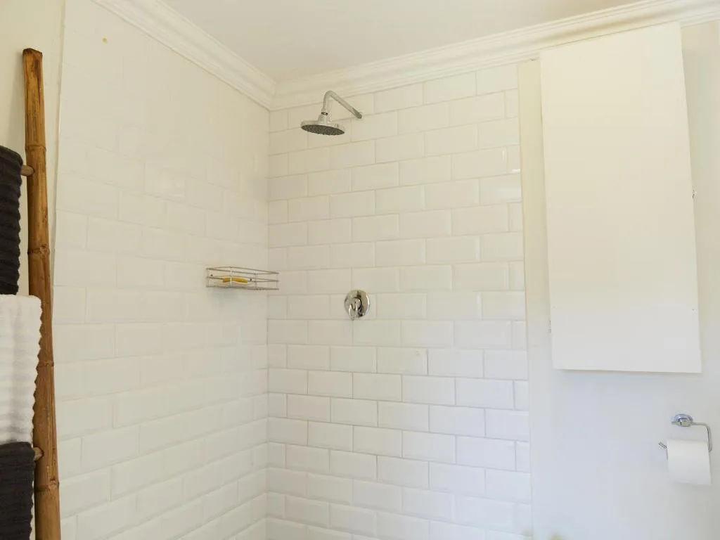Clean white subway tiled shower with rainfall showerhead and wall fixtures