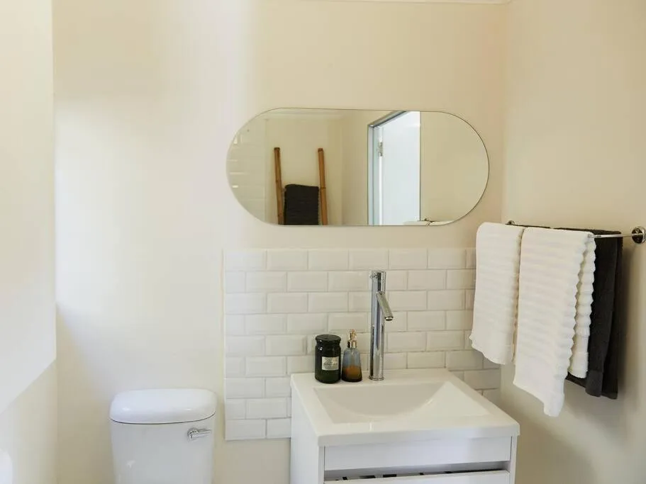Clean modern bathroom with white subway tiles, vanity sink, and toilet