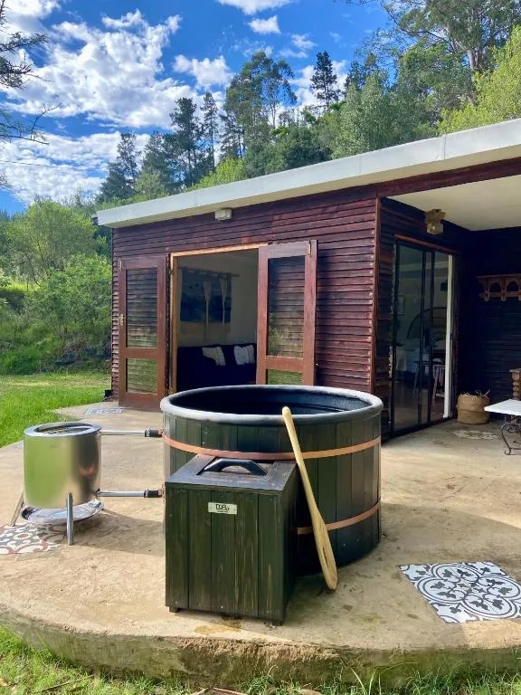 Wooden hot tub and fire pit on patio outside modern cabin