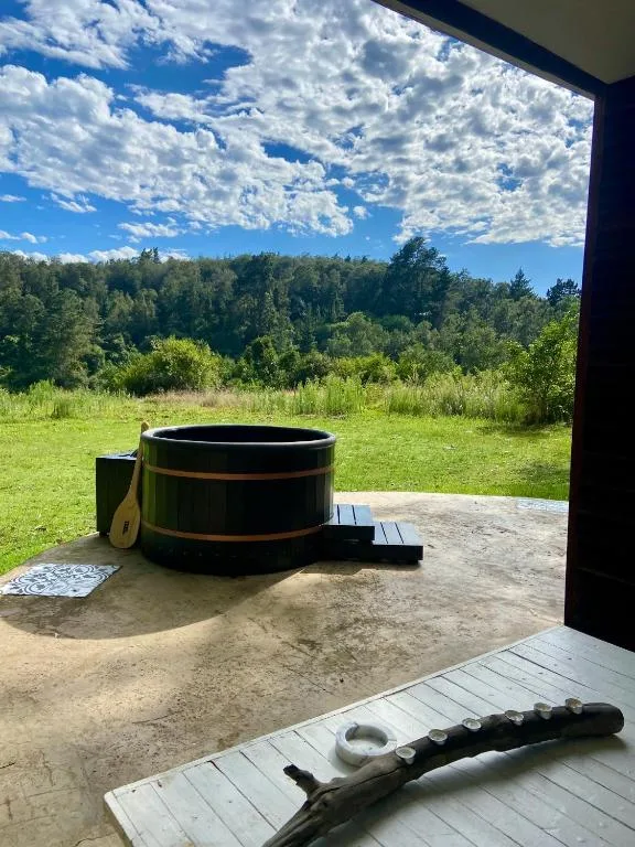 Hot tub on wooden deck overlooking lush green gardens and forest