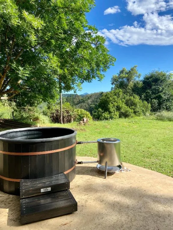 Black wooden hot tub with metal heating system on garden patio area