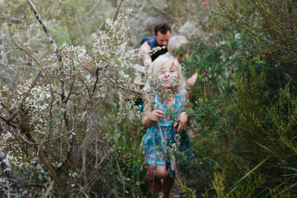Family walking through flowering garden path with white blooms