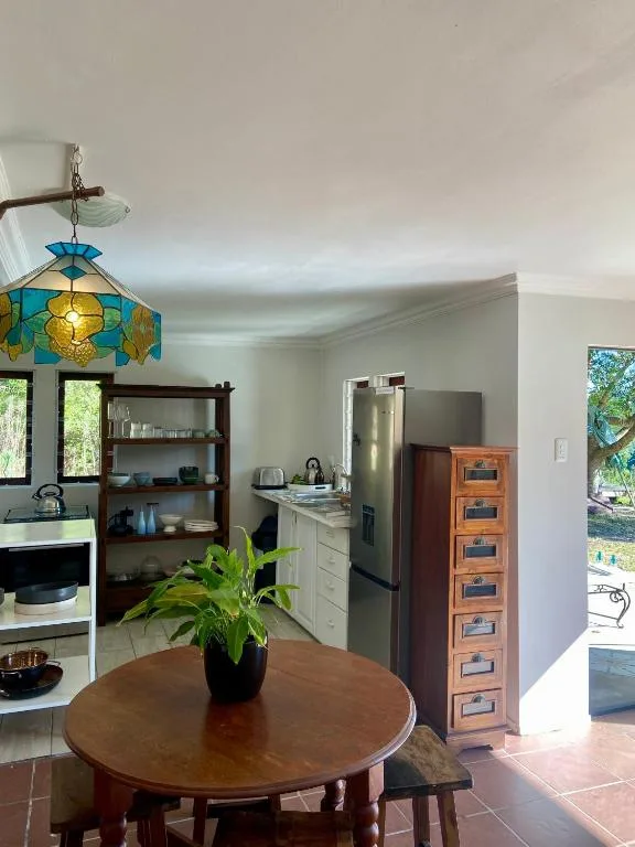 Open kitchen with stainless appliances, wooden dining table, and decorative pendant light