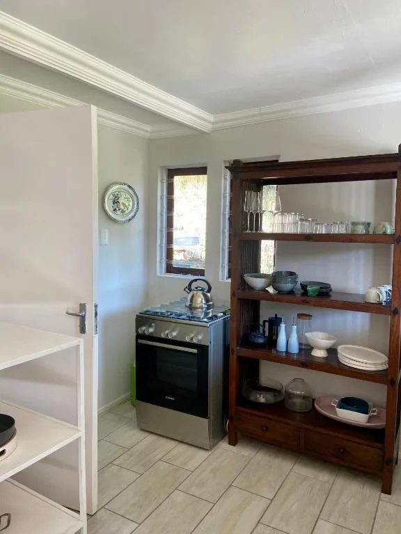 Compact kitchen with stainless steel stove and wooden open shelving storage