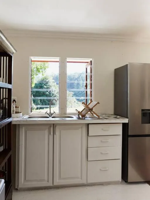 Modern kitchen with white cabinetry, stainless steel fridge, and scenic window views