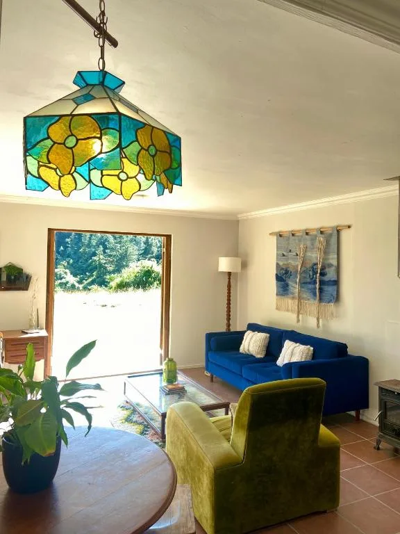 Bright lounge with blue sofa, yellow armchair, and stained glass pendant lamp