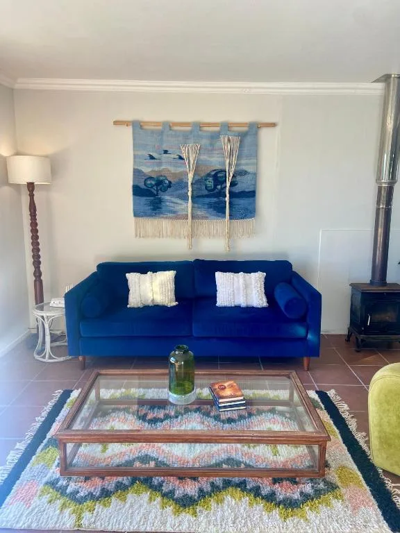 Bright living room with blue sofa, glass coffee table, and nautical wall art