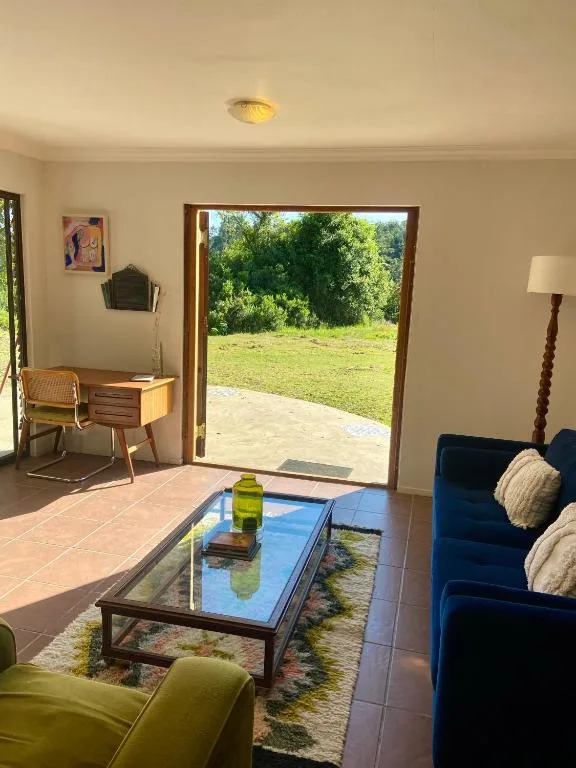 Bright lounge with blue sofa, green chair, and garden views through open doors