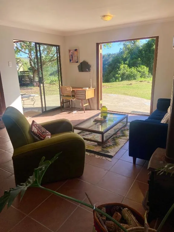 Bright lounge with armchairs, coffee table, and garden views through large doors