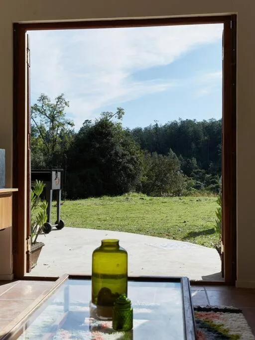 Lush green valley and forest landscape viewed through open glass doors