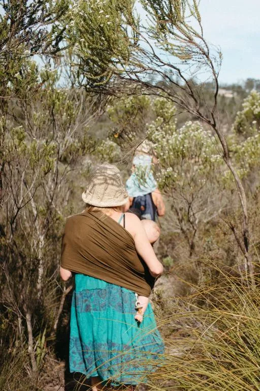 Woman walking through fynbos vegetation toward distant mountain landscape