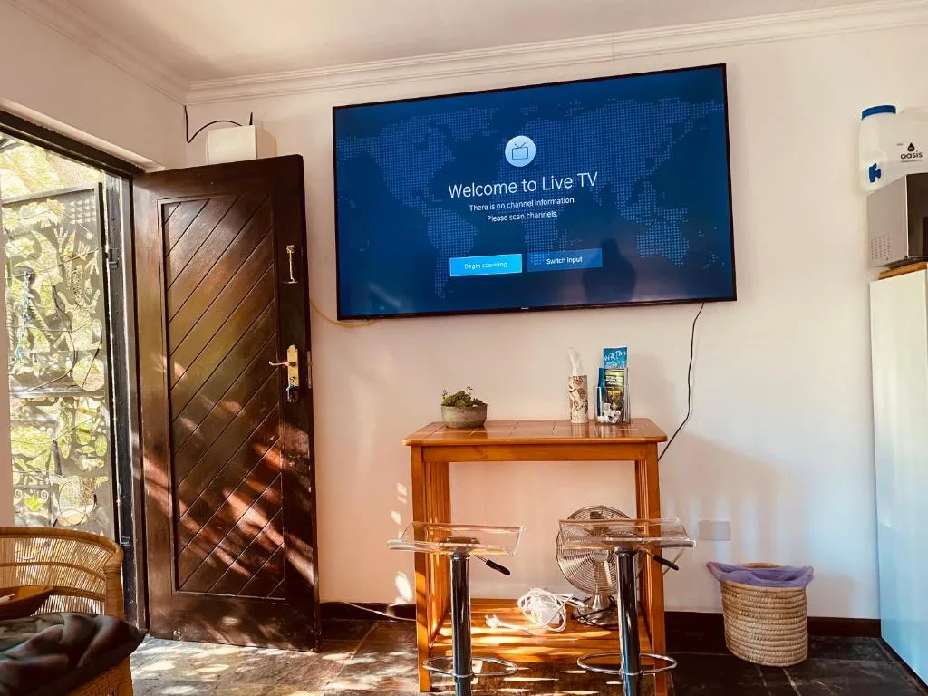 Bright living area with wall-mounted TV and wooden furnishings overlooking garden