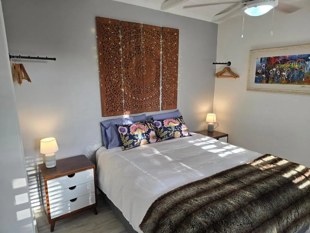 Bright bedroom with queen bed, decorative wooden headboard, and bedside lamps