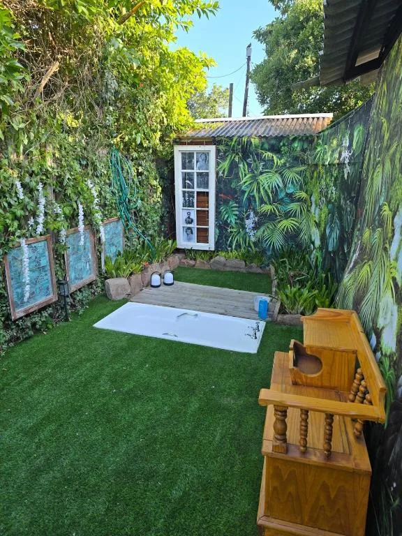 Lush garden courtyard with artificial grass, cornhole game, and storage cabinet