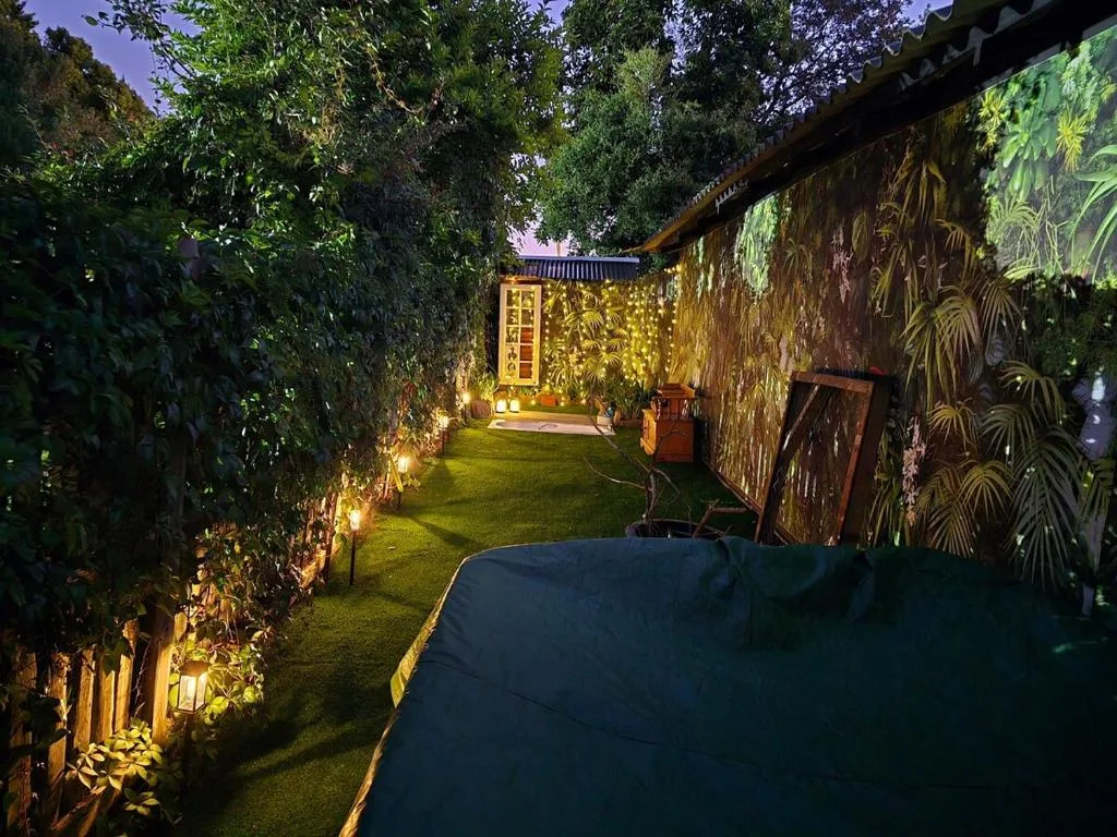 Illuminated courtyard garden with lawn, ivy walls, and seating area at dusk