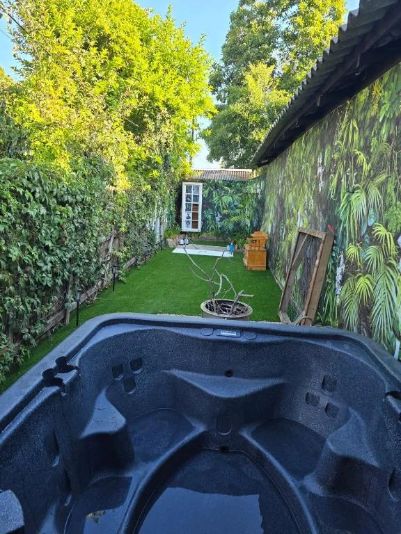 Intimate garden courtyard with hot tub, lush green lawn, and tropical wall mural
