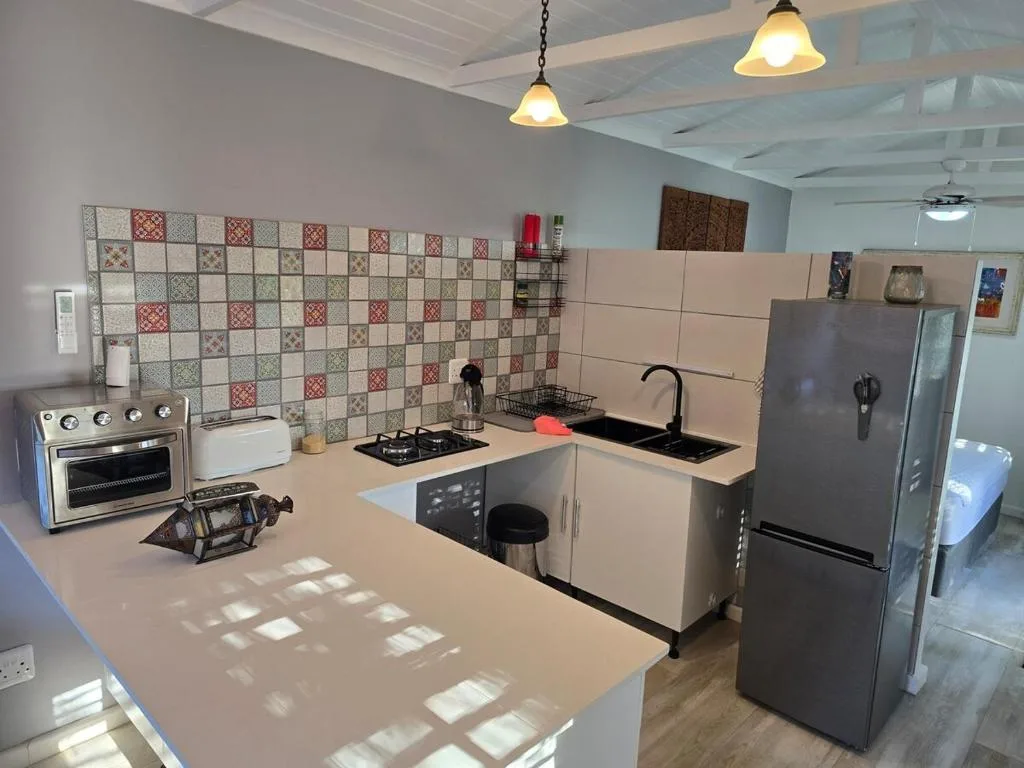 Modern kitchen with stove, sink, refrigerator, and patterned tile backsplash