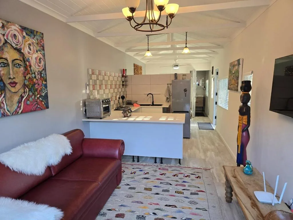 Open-plan lounge and kitchen with burgundy sofa and contemporary artwork