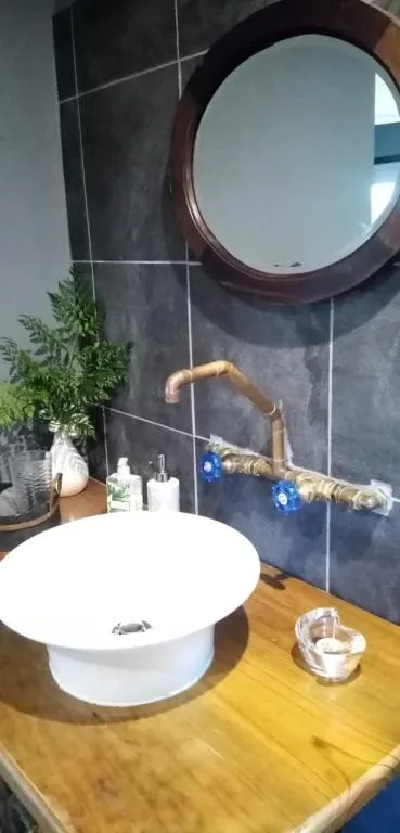 Modern bathroom with round mirror, white vessel sink, wooden vanity