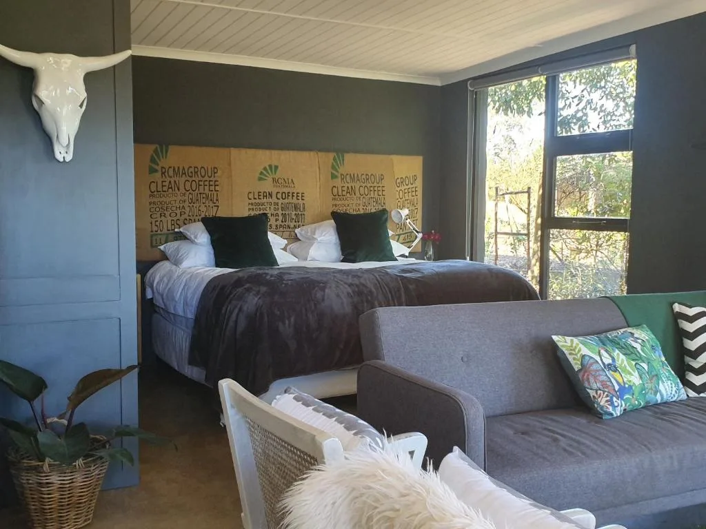 Spacious bedroom with queen bed, coffee-themed headboard, and lounge seating area