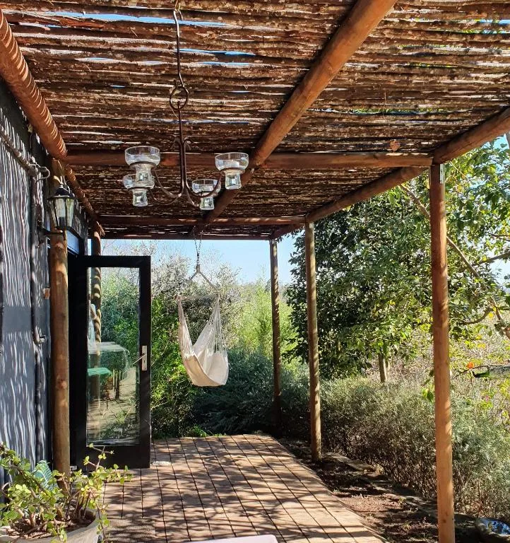 Rustic wooden pergola with hanging chair and garden views