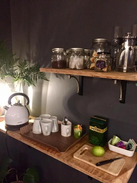 Kitchen corner with kettle, mugs, storage jars, and fresh fruit on wooden counters